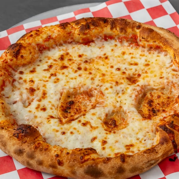 A close-up of a Flame and Cones cheese pizza with a golden crust on a red and white checkered paper.